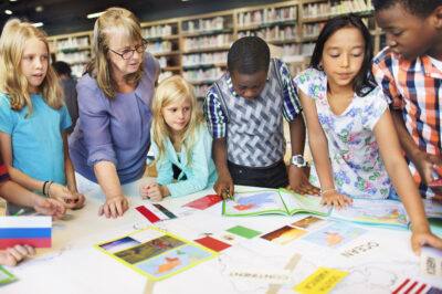 Students gathered around a table with their teacher engaged in an activity